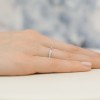 Delikatny pierścionek z białego złota wysadzany rzędem brylantów, prezentowany na dłoni na stonowanym tle produktu W0425.B3.DIW.01