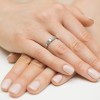 Elegancki pierścionek z białego złota 585 z czterema maleńkimi brylantami, prezentowany na dłoniach o jasnym manicure produktu W0417.B3.DIW.01