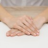 Złoty pierścionek z brylantem 0,03ct z kolekcji Klasyka, prezentowany na dłoni z beżowym manicure produktu W0461.Z3.DIW.02