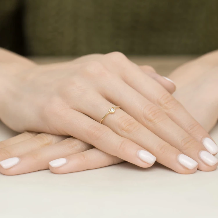 Złoty pierścionek z sercem i cyrkonią, prezentowany na dłoni produktu EP109-333