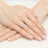 Pierścionek z białego złota z centralnym brylantem otoczonym mniejszymi brylantami, prezentowany na dłoniach z delikatnym manicure produkt W0551.B3.DIW.01