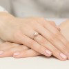 Elegancki pierścionek z różowego złota z centralnym brylantem o masie 0,50ct otoczonym przez 28 mniejszych brylantów, prezentowany na dłoni z delikatnym różowym lakierem do paznokci, produktu W0551.R3.DIW.02
