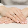 Elegancki pierścionek z białego złota z centralnym brylantem i dodatkowymi kamieniami na szynie, prezentowany na dłoni z jasnoróżowym manicure produktu W0534.B3.DIW.02