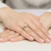 Elegancki pierścionek z białego złota z centralnie osadzonym brylantem o masie 1,00ct, zaprezentowany na dłoni z subtelnym różowym manicure produktu W0544.B3.DIW.04