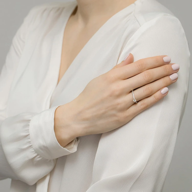 Elegancki pierścionek z białego złota ozdobiony błyszczącymi brylantami, prezentowany na damskiej dłoni produktu P157-B585-B0.29
