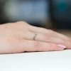 Delikatny pierścionek zaręczynowy z białego złota z małym brylantem, prezentowany na dłoni produktu W0181.B3.DIW.01