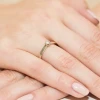 Delikatny pierścionek zaręczynowy z białego złota z jednym brylantem, prezentowany na dłoni z delikatnym, jasnym manicure produktu W0222.B3.DIW.03