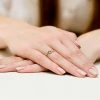 Delikatny pierścionek z białego złota z brylantami o łącznej masie 0,11 ct, prezentowany na dłoni z subtelnym manicure, produktu W0237.B3.DIW.01
