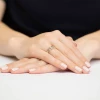 Delikatny pierścionek z białego złota z dwoma połączonymi sercami wysadzanymi brylantami, prezentowany na dłoni kobiety na jasnym tle produktu W0286.B3.DIW.01