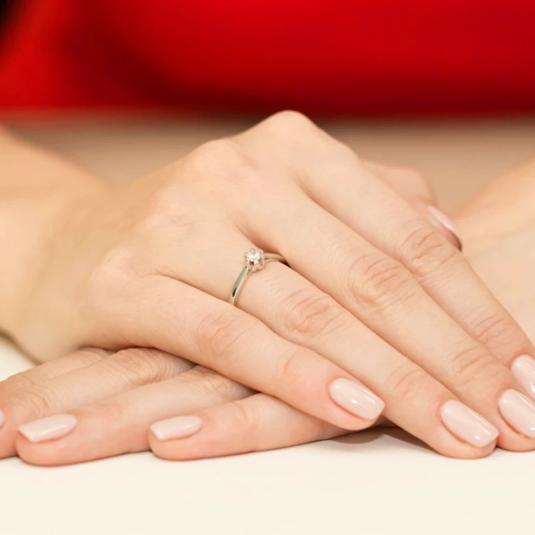 Klasyczny pierścionek z białego złota z brylantem, prezentowany na dłoni z idealnie wykonanym manicure, produktu W0299.B3.DIW.01