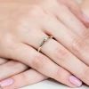 Białe złoto pierścionka zaręczynowego z delikatnym brylantem osadzonym na smukłej obrączce, prezentowanego na kobiecej dłoni z paznokciami w kolorze pudrowego różu, produktu W0317.B3.DIW.01