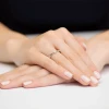 Delikatny pierścionek zaręczynowy z białego złota z jednym brylantem centralnie osadzonym na wąskiej obrączce, prezentowany na dłoni produktu W0322.B3.DIW.01