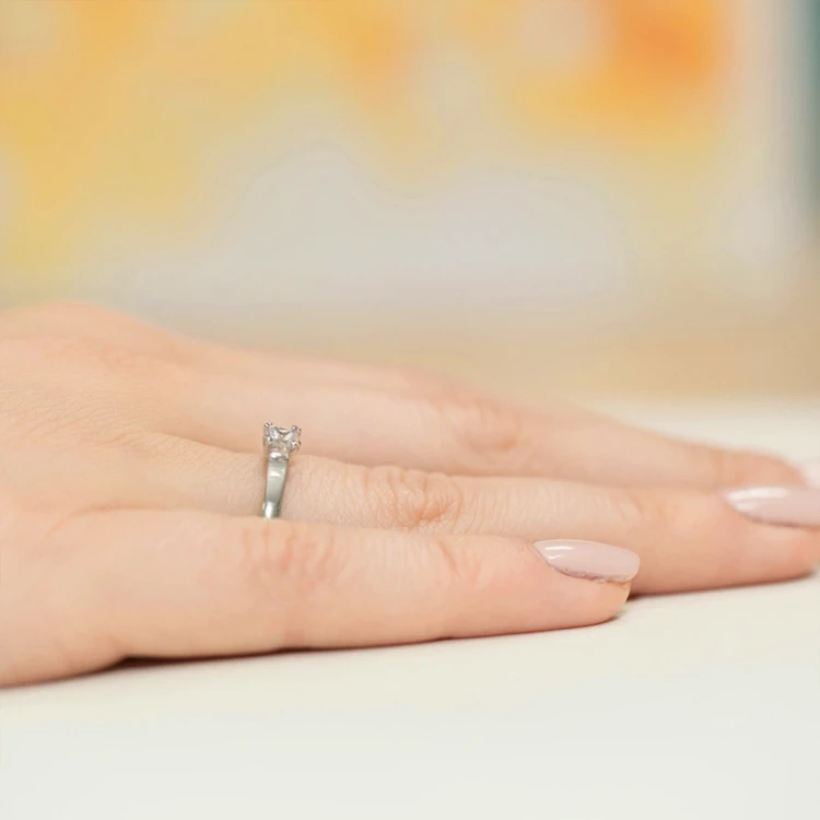Białe złoto pierścionka z diamentem w szlifie princessa, prezentowany na dłoni produktu W0347.B3.DIW.01