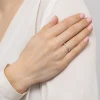 Delikatny pierścionek z białego złota z pojedynczym brylantem, prezentowany na dłoni ubranej w białą koszulę, produktu W0512.B3.DIW.01