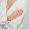 Elegancki złoty pierścionek z szeroką obrączką wysadzaną lśniącymi cyrkoniami, prezentowany na dłoni kobiety ubranej w białą, zwiewną bluzkę, produktu P179-585-B