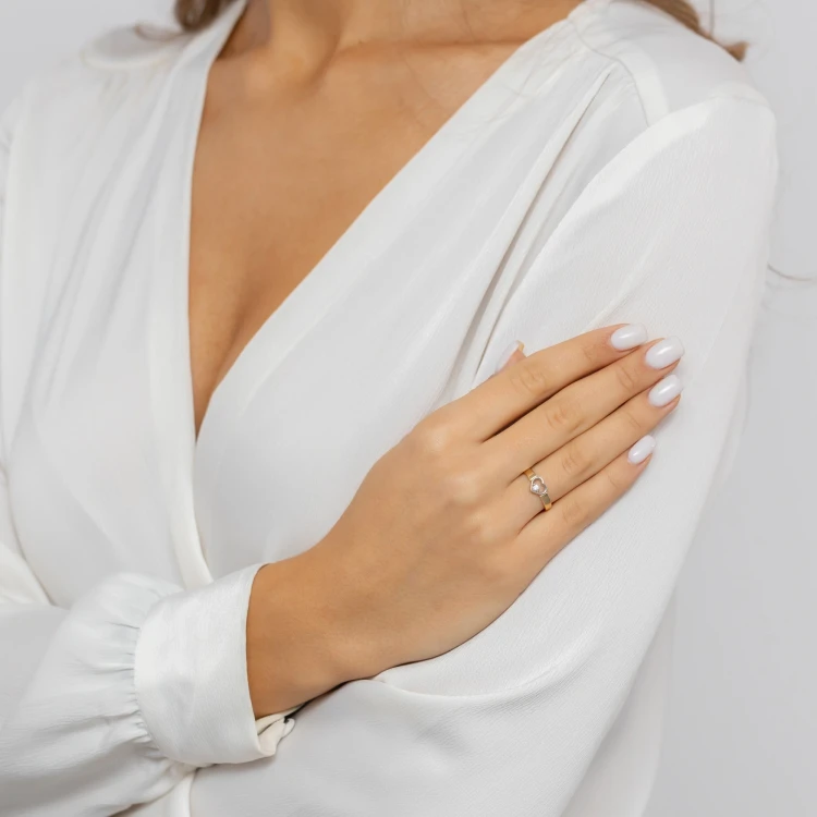 Złoty pierścionek z sercem ozdobionym cyrkonią, prezentowany na dłoni z białym manicure produktu P190-333-B