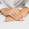 Elegancki pierścionek z żółtego złota z prostokątnym morganitem otoczonym błyszczącymi cyrkoniami, prezentowany na dłoni z białym manicure, produktu W0575.Z3.MOP.01