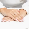 Delikatny złoty pierścionek ozdobiony białymi cyrkoniami, prezentowany na dłoni z zadbanym manicure, produktu EP174-333-B