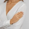 Złoty pierścionek z owalnym, białym oczkiem z cyrkonii, prezentowany na dłoni z białym manicure produktu P191-333-B