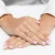 Złoty pierścionek zaręczynowy z dwoma skrzyżowanymi obrączkami, z czego jedna jest wysadzana drobnymi cyrkoniami, prezentowany na dłoni z manicure w stylu francuskim produktu P175-333-B