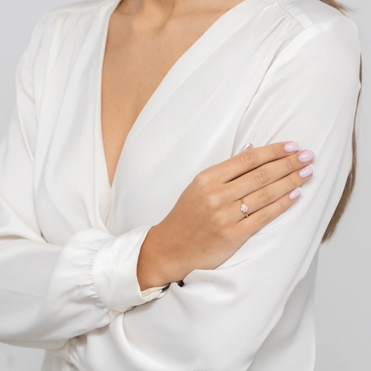 Delikatny złoty pierścionek z owalną, błyszczącą białą cyrkonią osadzoną na subtelnej obrączce, prezentowany na dłoni modelki na jasnym tle produktu EP178-333-B