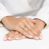 Złoty pierścionek z ciemną cyrkonią w okrągłej oprawie, prezentowany na dłoni z frenczowym manicure na białym tle produktu AP142-585-CZ