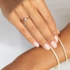 Delikatny pierścionek zaręczynowy z żółtego złota z pojedynczym, błyszczącym diamentem laboratoryjnym, prezentowany na dłoni z naturalnym manicure produktu W0256.Z3.LDW.01