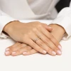Złoty pierścionek z delikatną, skręconą obrączką wysadzaną małymi cyrkoniami i centralną łezką, prezentowany na dłoniach z delikatnym manicurem produktu EP199-333-B