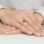 Złoty pierścionek z owalną cyrkonią w kolorze rubinowym, prezentowany na dłoni z delikatnym manicure produktu P130-333-C