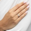 Elegancki pierścionek z białego złota z kwadratowym diamentem Princessa oraz drobnymi brylantami, prezentowany na dłoni produktu W0591.B3.DIW.01