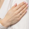 Delikatny pierścionek zaręczynowy z różowego złota z centralnie osadzonym diamentem laboratoryjnym oraz drobnymi kamieniami wysadzanymi wzdłuż obrączki, prezentowany na dłoni produktu W0052.R3.LDW.01