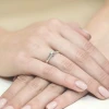 Elegancki pierścionek zaręczynowy z białego złota z brylantem o masie 0,12 ct, prezentowany na dłoni produktu W0088.B3.DIW.05
