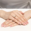 Złoty pierścionek z małą, okrągłą, granatową cyrkonią, prezentowany na dłoni z manicure w stylu francuskim produktu W0045.Z6.ZIN.01