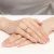 Złoty pierścionek z małą, okrągłą, granatową cyrkonią, prezentowany na dłoni z manicure w stylu francuskim produktu W0045.Z6.ZIN.01