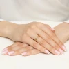 Złoty pierścionek z ażurowym, geometrycznym wzorem, prezentowany na dłoni z francuskim manicure, produktu AP199-585