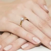 Elegancki, klasyczny pierścionek zaręczynowy z żółtego złota z błyszczącym, okrągłym diamentem laboratoryjnym o szlifie brylantowym, prezentowany na dłoni produktu W0222.Z3.LDW.09