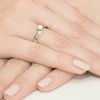 Subtelny dwukolorowy złoty pierścionek z pojedynczym diamentem laboratoryjnym, prezentowany na dłoni z delikatnym manicure produktu W0231.Z3.LDW.05