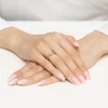 Złoty pierścionek z delikatną, owalną akwamaryną osadzony na subtelnej obrączce, prezentowany na dłoni z paznokciami w stylu francuskiego manicure produktu W0685.Z3.AQB.01