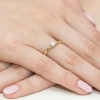 Złoty pierścionek z diamentem prezentowany na dłoni kobiety z jasnym tłem produktu W0240.Z3.DIW.01