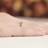 Elegancki pierścionek zaręczynowy w kolorze żółtego złota z pojedynczym, błyszczącym diamentem, prezentowany na dłoni na stonowanym, jasnym tle produktu W0229.Z3.DIW.03