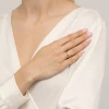 Delikatny złoty pierścionek z pojedynczą, błyszczącą cyrkonią, prezentowany na dłoni kobiety odzianej w białą, elegancką bluzkę, produktu P202-333-B