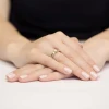 Złoty, szeroki pierścionek obrączkowy z centralnie osadzonym diamentem laboratoryjnym oraz dodatkowymi mniejszymi diamentami po bokach, prezentowany na dłoni produktu W0356.Z3.LDW.01