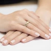 Elegancki złoty pierścionek z centralnie osadzonym diamentem laboratoryjnym oraz licznymi mniejszymi kamieniami na szerokiej obrączce, prezentowany na dłoni produktu W0356.Z3.LDW.01