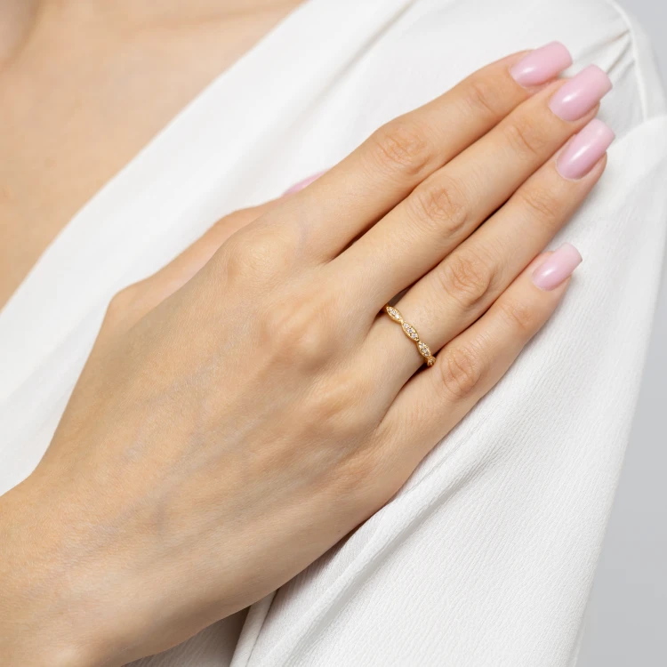 Złoty, falowany pierścionek z wieloma małymi cyrkoniami, prezentowany na dłoni z jasnoróżowym manicure produktu P205-333-B