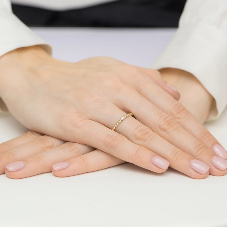 Złoty pierścionek obrączka z brylantem Soledo, prezentowany na dłoni z subtelnym manicure produktu W0601.Z3.DIW.01