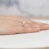 Delikatny pierścionek zaręczynowy z różowego złota z okrągłym diamentem laboratoryjnym 0,50ct i mniejszymi diamentami, prezentowany na dłoni produktu W0451.R3.LDW.01
