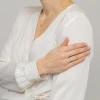 Smukły pierścionek z białego złota z jednym brylantem, prezentowany na dłoni z manicure w kolorze pudrowego różu, produktu W0464.B3.DIW.01