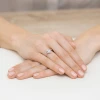 Delikatny pierścionek z różowego złota z centralnie osadzonym diamentem łezką w otoczeniu mniejszych diamentów laboratoryjnych, prezentowany na dłoni produktu W0455.R3.LDW.01