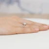 Elegancki pierścionek z różowego złota z centralnie osadzoną łezką diamentową otoczoną mniejszymi diamentami laboratoryjnymi, prezentowany na dłoni produktu W0455.R3.LDW.01