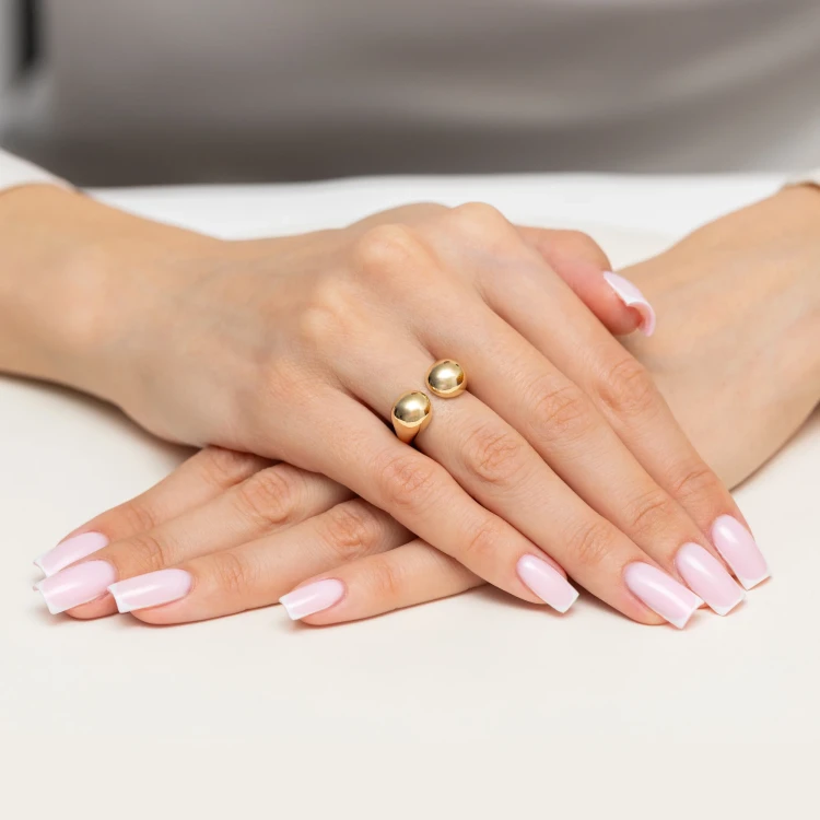 Złoty pierścionek z gładkimi kulkami, prezentowany na dłoni z jasnoróżowym, francuskim manicure produktu P-GW-029-585